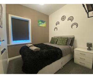 a bedroom with a bed with a black blanket and a window at Bank Street Apartment 7 in Blackpool