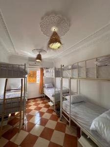 a room with four bunk beds and a checkered floor at Olas Surf House in Imsouane