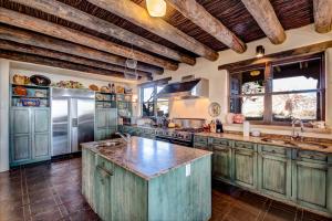 a large kitchen with wooden ceilings and a large island at El Otro Mundo in Santa Fe