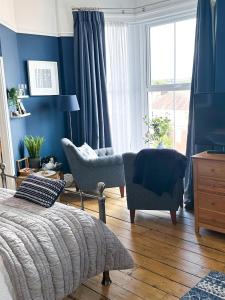 a bedroom with blue walls and a bed and chairs at View at 142 in The Mumbles