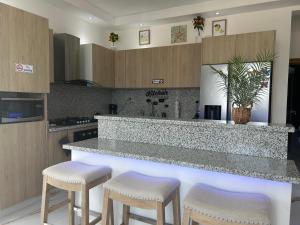 a kitchen with a counter with stools in it at Acogedor Apartamento Familiar con piscina. in Boca Chica