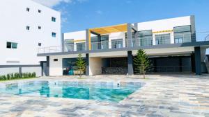a house with a swimming pool in front of a building at Acogedor Apartamento Familiar con piscina. in Boca Chica