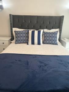 Una cama con almohadas azules y blancas. en Acogedor Apartamento Familiar con piscina., en Boca Chica