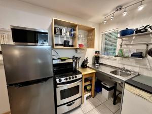 Una cocina con frigorífico de acero inoxidable y fregadero. en Cozy Cabin Centrally Located Close To Walking Trails And Beaches!, en Ucluelet 8 fotos más