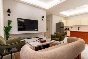 ein Wohnzimmer mit einem Sofa, Stühlen und einem TV in der Unterkunft Nuzul R154 - Elegant Apartment in Riad