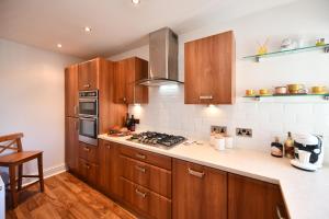 uma cozinha com armários de madeira e um forno com placa de fogão em The Lemon Tree em Prestwick