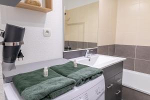 een badkamer met een wastafel en een groene handdoek bij Le Beluga – Appartement proche Airbus in Colomiers