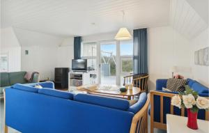 a living room with a blue couch and a table at Awesome Home In Blvand With 3 Bedrooms, Wifi And Sauna in Blåvand