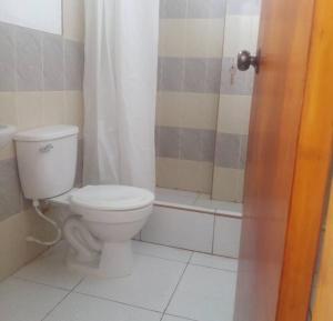 a bathroom with a white toilet and a shower at Dylan Beach in Zorritos