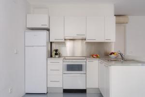 una cocina blanca con electrodomésticos blancos y armarios blancos en Sa Tuna 1- Cal Guarda, en Begur