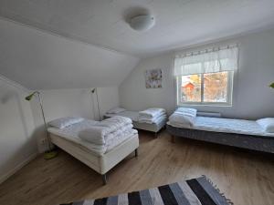 a room with three beds and a window at Romme stugby in Borlänge