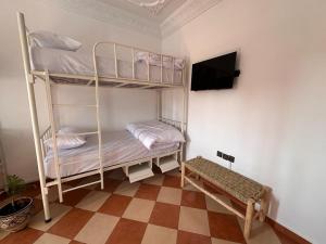a room with two bunk beds and a flat screen tv at Olas Surf House in Imsouane