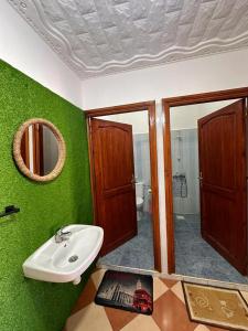 Baño verde con lavabo y espejo en Olas Surf House, en Imsouane