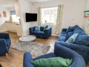 a living room with a blue couch and chairs at Aldrich Cottage in Kilmersdon