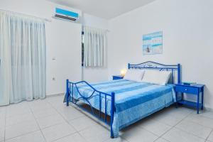 uma cama azul num quarto branco com uma moldura azul em Xenios Loutra Village Arsinoi Studios em Agia Paraskevi
