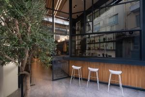 a bar with white stools in front of a building at Nema Hotel Athens in Athens