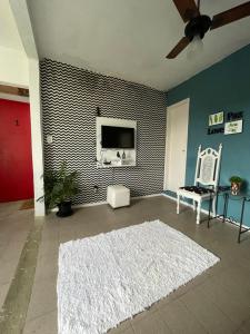 a living room with a tv and a white rug at Aconchego Penedo in Penedo
