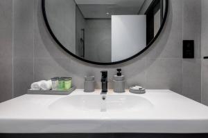 een badkamer met een wastafel met een spiegel en een wastafel bij Waves Holiday Homes - 15 Northside, Tower 1, Two Bedroom in Dubai