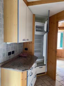 ポッツァ・ディ・ファッサにあるCasa Lasteiの白いキャビネットと空の冷蔵庫付きのキッチンが備わります。