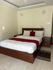 Schlafzimmer mit einem großen Bett mit weißer und roter Bettwäsche in der Unterkunft Nagarkot Resort PVt. Ltd in Nagarkot