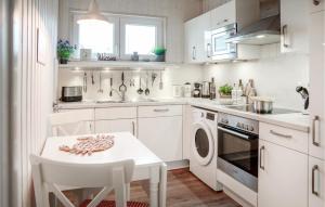 eine Küche mit weißen Schränken, einem Tisch und einem Waschbecken in der Unterkunft Kuschelhaus in Olpenitz