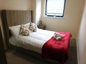 a bed with a teddy bear on a red blanket at Fabulous 2 bed apt 10 mins from City Centre in Glasgow