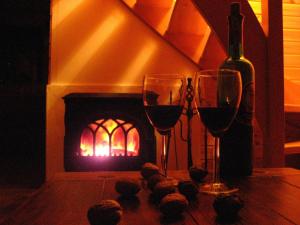 - deux verres à vin et une bouteille de vin devant la cheminée dans l'établissement Wierzbowy Jar - Natura Spokój Sauna Kominek Karkonosze, à Janowice Wielkie