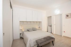 a white bedroom with a large bed and a bench at Affittacamere LE RONDINI in Domus de Maria