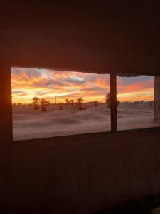 a window in a room with a sunset in the desert at Riad ma bonne étoile in Kasr Bounou