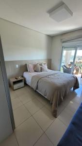 弗洛里亚诺波利斯Suas férias com todo conforto PÉ NA AREIA的一间卧室，里面有一张床和一扇大窗户。