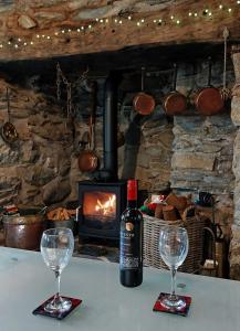 a bottle of wine sitting on a table with two glasses at Cae Tudur Remote Rural Cottage near Barmouth in Barmouth