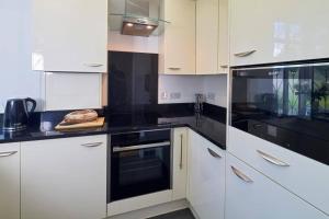 a kitchen with white cabinets and black appliances at BOURNECOAST: GROUND FLOOR - GARDEN - WIFI - FM6096 in Iford