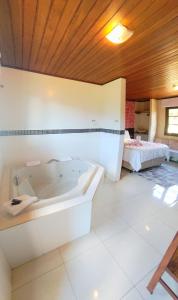 a large bathroom with a tub and a bed at Chalés Leopoldo em Monte Verde in Monte Verde