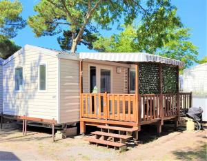 uma pequena casa com um alpendre e um deque em Bungalow de 2 chambres avec piscine partagee terrasse amenagee et wifi a Saint Jean de Monts a 1 km de la plage em Saint-Jean-de-Monts