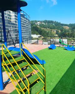 un parque infantil con toboganes azules y amarillos y césped en Nagarkot Resort PVt. Ltd, en Nagarkot