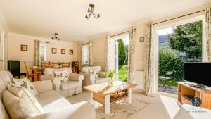 a living room with white furniture and a tv at Wildflower Cottage - Sutton Poyntz in Preston