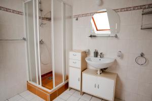 La salle de bains blanche est pourvue d'un lavabo et d'une douche. dans l'établissement Penzion Harmonia, à Liptovský Mikuláš