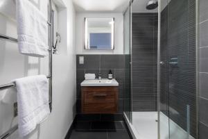 uma casa de banho com um lavatório e uma cabina de duche em vidro. em Divine Views from a Breathtaking LuxXe City Penthouse for a Gracious Life Style em Londres