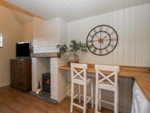 a room with a fireplace with a clock and stools at The Annex in Pershore
