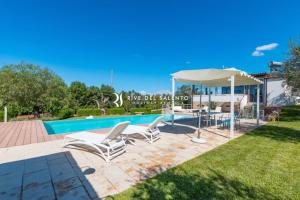 een zwembad met 2 ligstoelen en een parasol bij Villa Micasa RivedelSalento in Collepasso