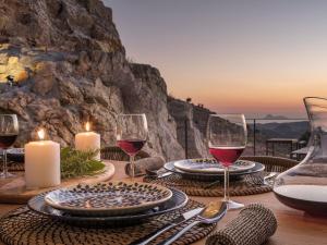 a table with glasses of red wine and candles at Askianos Luxury Villas - An Oasis of Harmony & Elegance in Lístaros