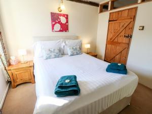 FeethamにあるPursglove Cottageのベッドルーム1室(白いベッド1台、青いタオル付)