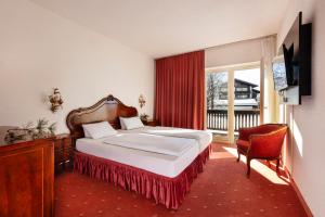 ein Schlafzimmer mit einem Bett und einem großen Fenster in der Unterkunft Alpenhof in Seefeld in Tirol
