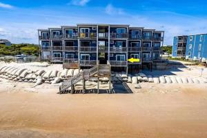a building on the beach with a sandy beach at Seaside Joy - This is your happy place! in North Topsail Beach