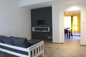 a living room with a couch and a tv on a wall at Casa de Playa in Puerto Madryn