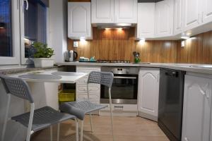 a kitchen with white cabinets and a table and chairs at Apartament Chorzów Centrum Wróblewskiego in Chorzów