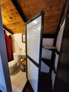 a bathroom with a toilet and a glass door at Hospedaje Las Cabañas in Monguí