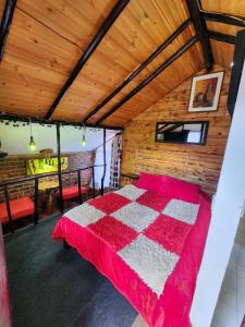 a bedroom with a red and white bed in a room at Hospedaje Las Cabañas in Monguí