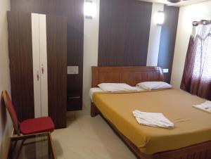 a bedroom with two beds and a red chair at Hotel Western Park in Port Blair