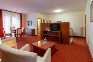 a living room with a couch and a tv and a table at Das kleine Amtshotel 